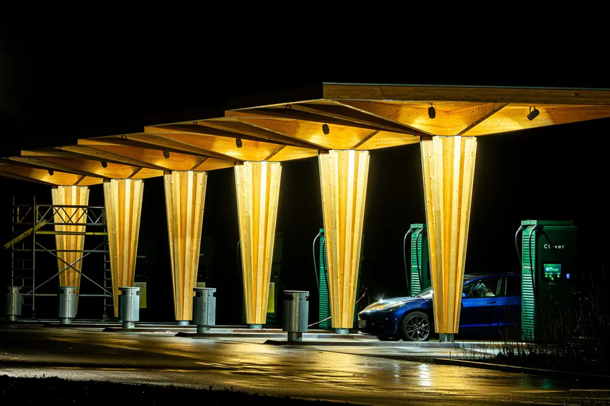 Charging bays under a lit timber canopy at night
