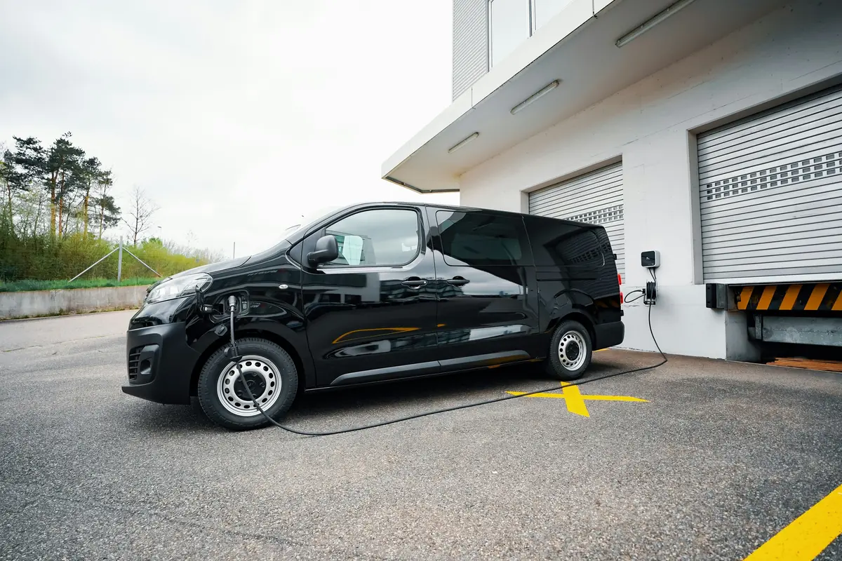 An electric van charging at a wall unit outside a depot