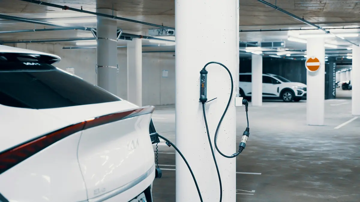 A charger on a garage column, its cable plugged into a car