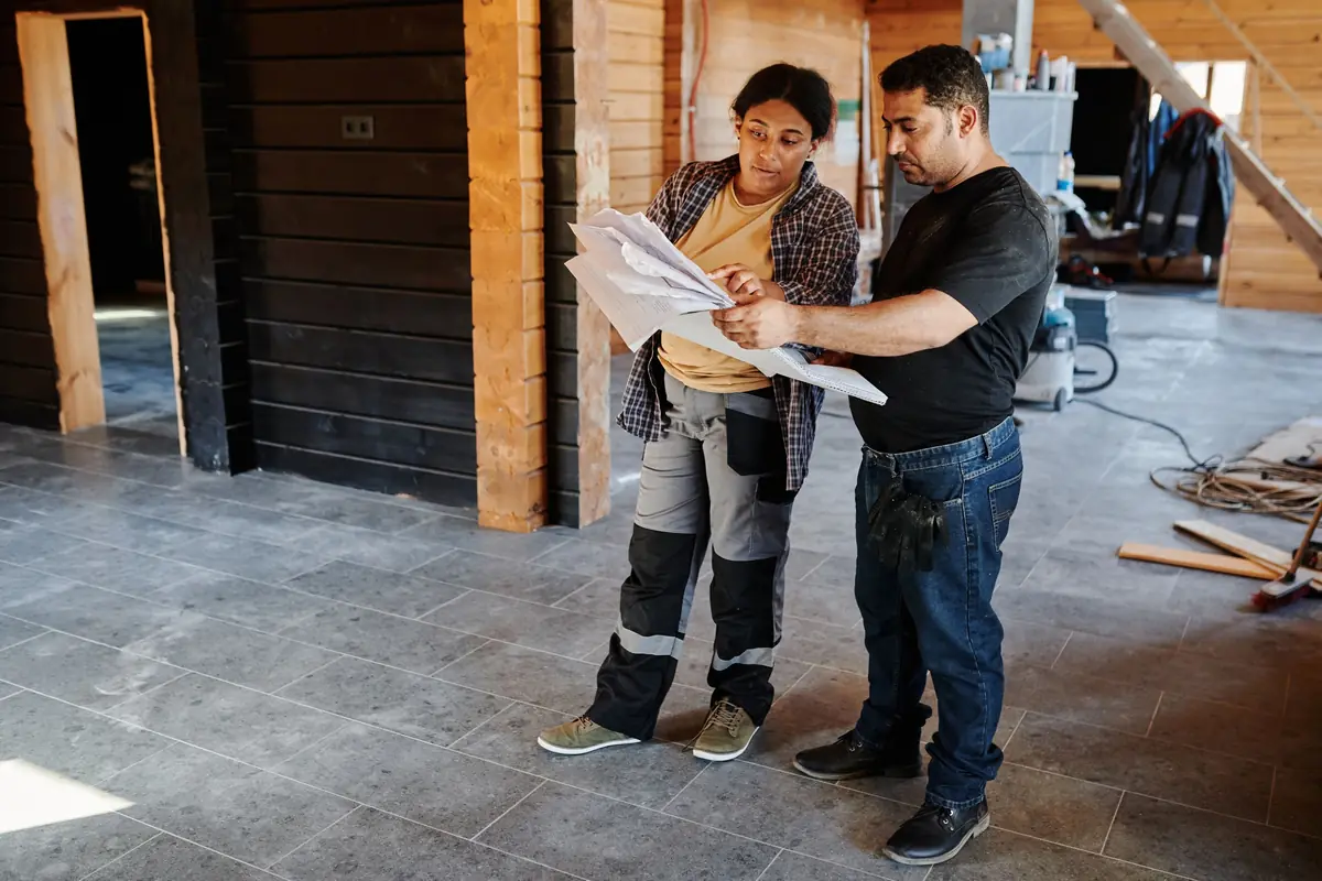 Two people look over plans on a renovation site