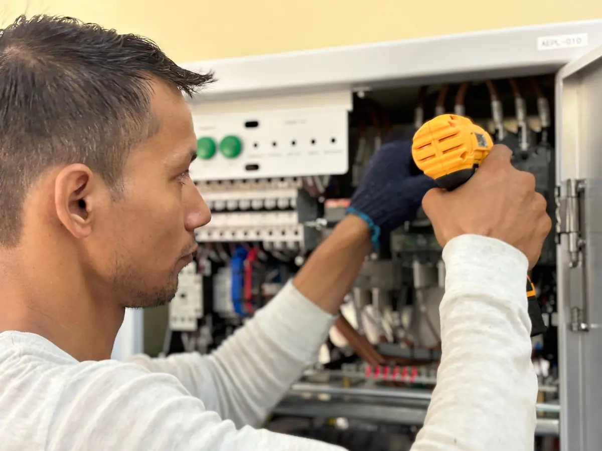 An electrician working in an open electrical panel