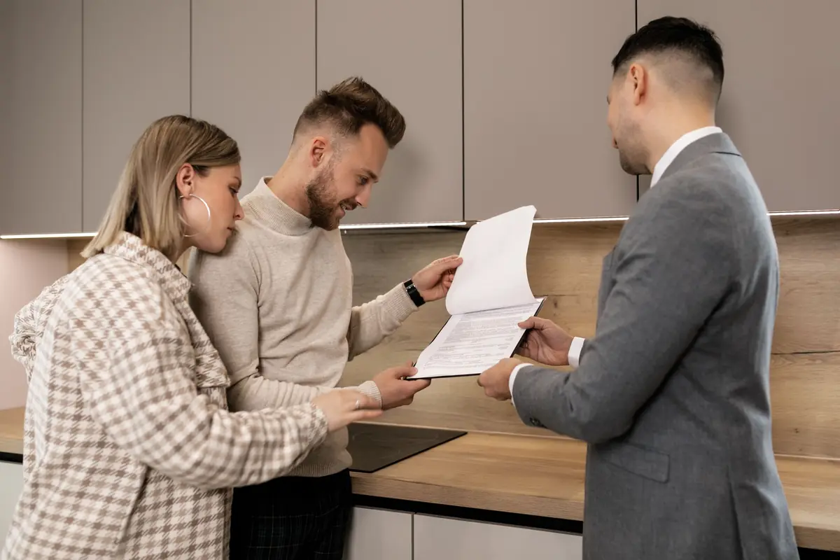 A couple reviews a document with an adviser in their kitchen