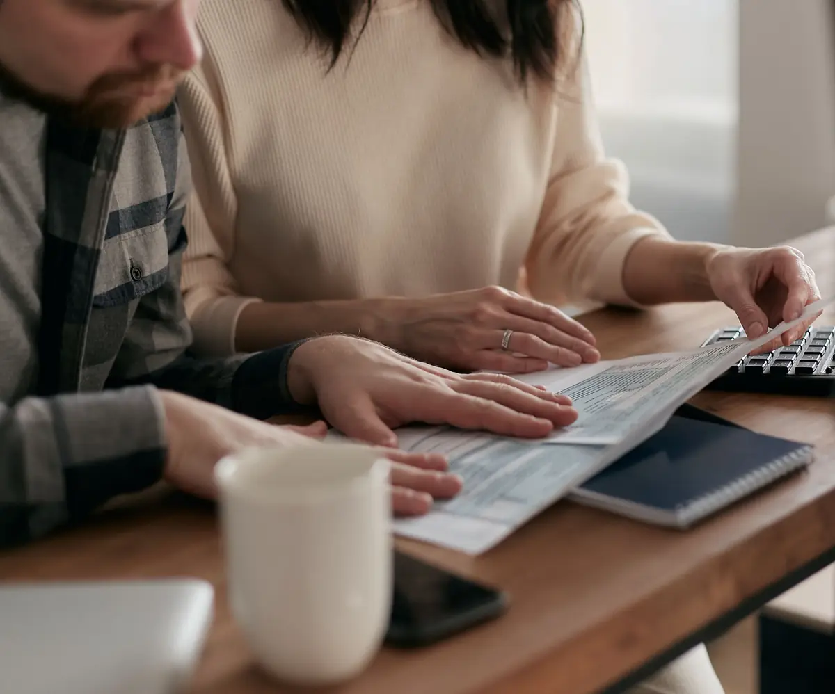 Two people go through paperwork at a desk