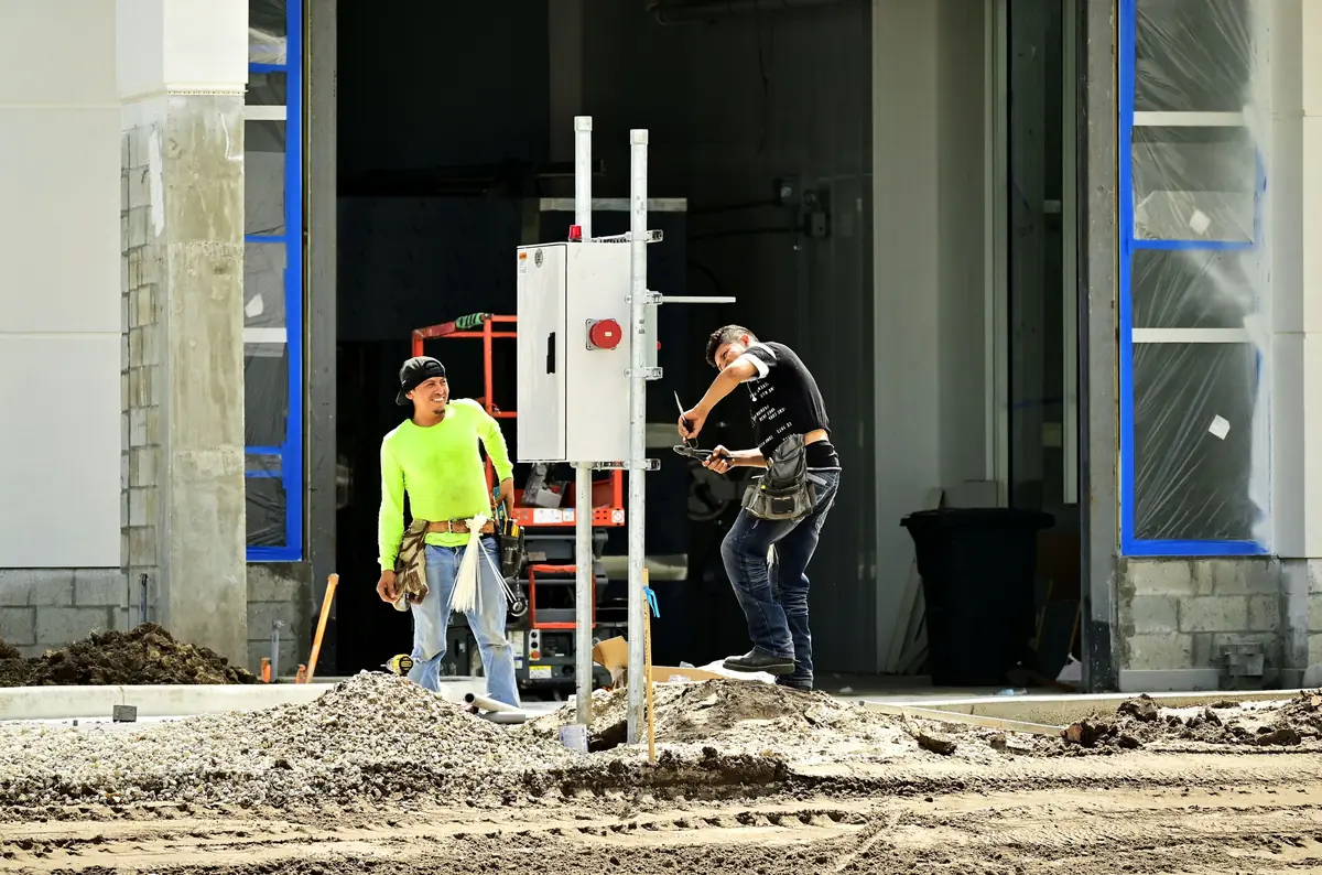 Electricians install equipment on a commercial building site