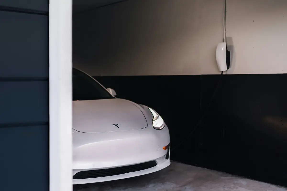 A car parked in a garage below a wall charger