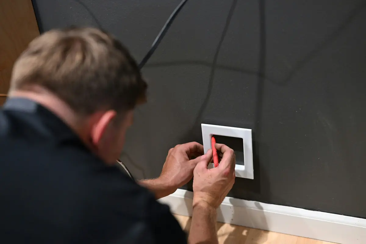 An electrician fits a wall box in a garage